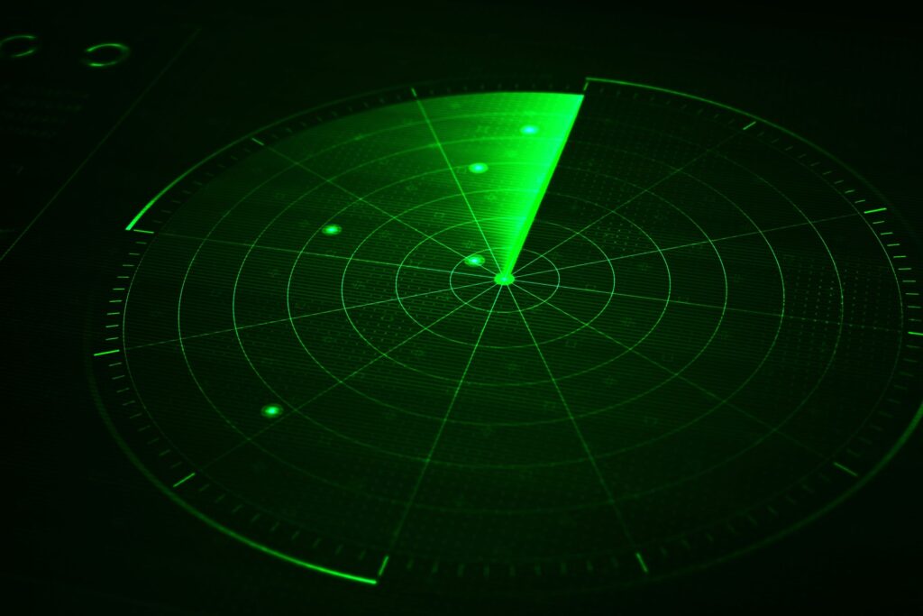A glowing green radar screen shows a sweeping beam and dots indicating detected objects.